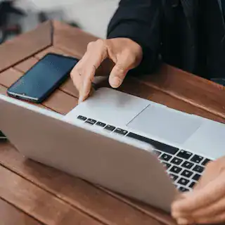 Ordinateur portable sur une table en bois dans un espace de coworking moderne. Site Web Professionnel : Les Secrets des Entreprises Qui Réussissent
